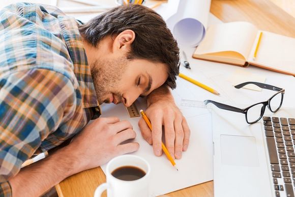 Mann schläft in seinem Büro auf dem Schreibtisch