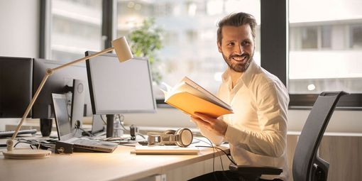 Mann lachend am Schreibtisch im Büro