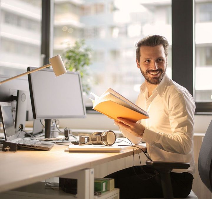 Mann lachend am Schreibtisch im Büro