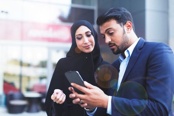 Geschäftsfrau und -mann bei Arbeit in Dubai mit Smartphone