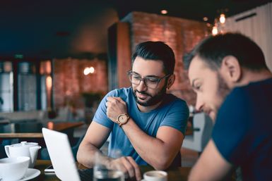 zwei Männer sitzen zusammen und arbeiten