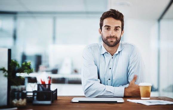 Mann sitzt zufrieden im Büro.