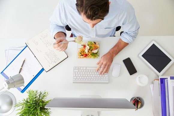 Bürotisch von oben mit Mann und gesundem Essen