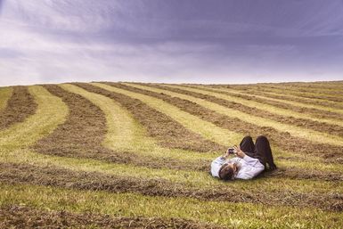 Mann liegt im Feld mit seinem Handy